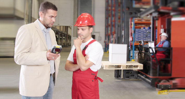 Ein Steuerberater unterhält sich in einer Produktionshalle mit einem Unternehmer über Betriebswirtschaftliche Beratung.